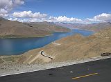 Tibet 05 01 Yamdrok Tso Kamba La The road from Lhasa to Gyantse (260km) took us over two mountain passes. From the Kamba La (4794m), we had a fantastic view of the beautiful Yamdrok Tso (Turquoise lake) with Nojin Kangtsang (7191m) behind, hidden in the clouds. In the foreground is the new paved road just opened in June 2005, in preparation for the 40th anniversary of the creation of the Tibet Autonomous Region.